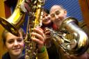 Karen Barden (centre) receives the saxophones from Emma Lifshitz and Roy Wilkinson