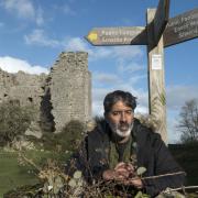 EXPLORING: Nihal Arthanayake under a footpath sign next to Arnside Tower for BBC Four's Winter Walks.  Photograph: Tim Smith