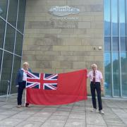 The Chairman of Cumbria County Council, Cllr Andy Connell and Cabinet Member and Armed Forces Portfolio Holder, Cllr Celia Tibble with the Red Ensign outside Cumbria House, Carlisle.