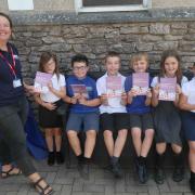 Amanda Walters from the Westmorland Dales Landscape Partnership Scheme distributing printed copies of Legends of the Westmorland Dales to children from Years 3.