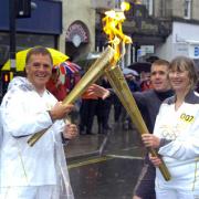 John Roelich takes the Olympic flame from Cate Davies in Kendal Town Centre.