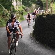 Cyclists battle up the steep section of road leading to The Struggle at Ambleside