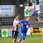 Gavin Clark wins a header during the match against Kidsgrove Athletic