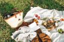 A picnic blanket and items laid out on the grass. Credit: Canva