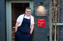 Ryan Blackburn stands next to the recognition of the Old Stamp House's Michelin Star