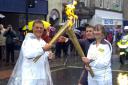 John Roelich takes the Olympic flame from Cate Davies in Kendal Town Centre.