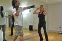 Trainer Louis Mackay shows Suzi the moves for ‘Body Combat.’