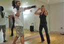 Trainer Louis Mackay shows Suzi the moves for ‘Body Combat.’